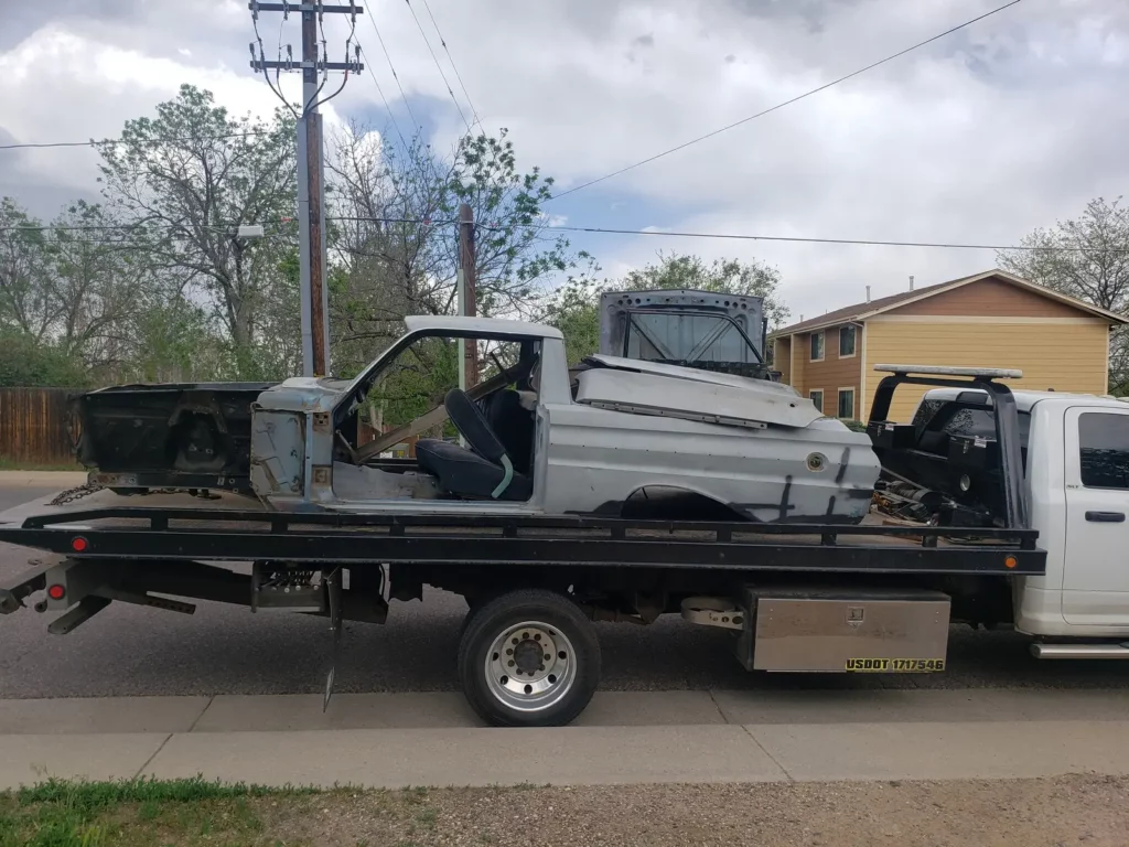 Stripped and dismantled pickup truck shell loaded on a flatbed, junk car buyer serving Watkins, CO