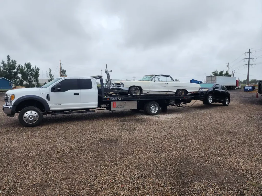 Jorge's family-owned tow truck hauling an old classic convertible and an SUV, junk car buyer in Denver