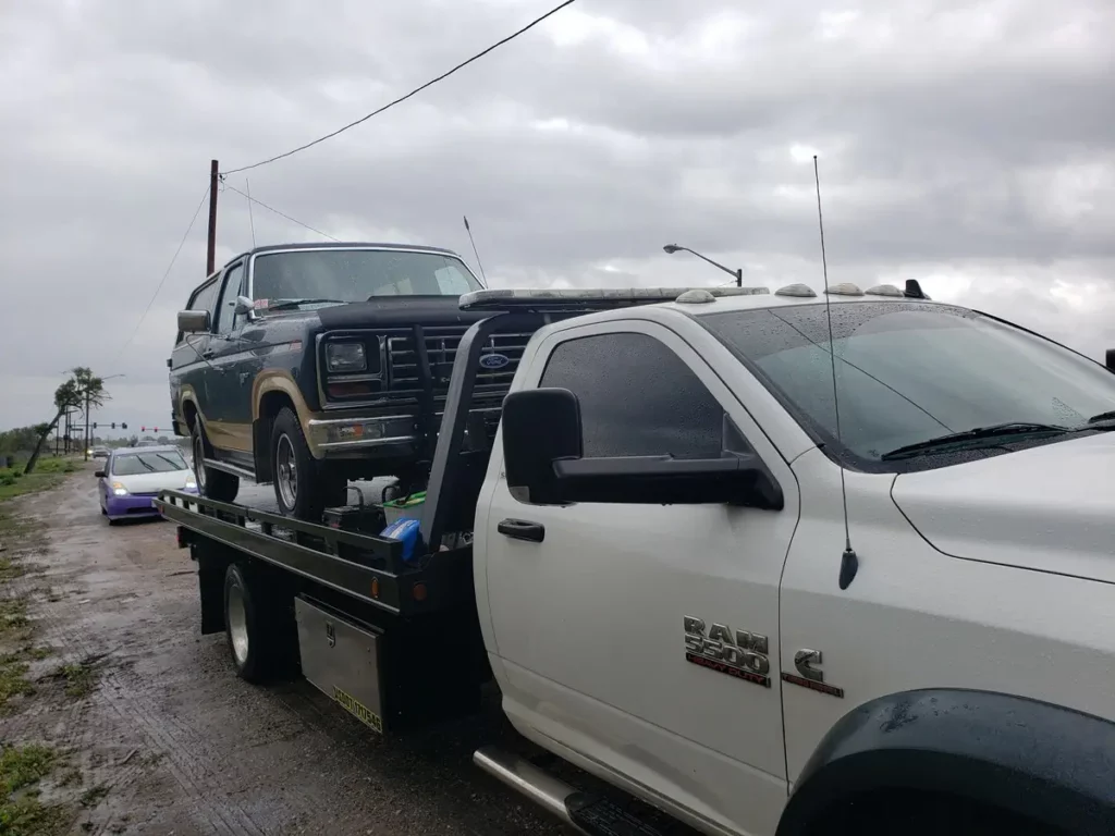 Ram flatbed hauling an old Ford truck, junk car removal serving Loveland, CO