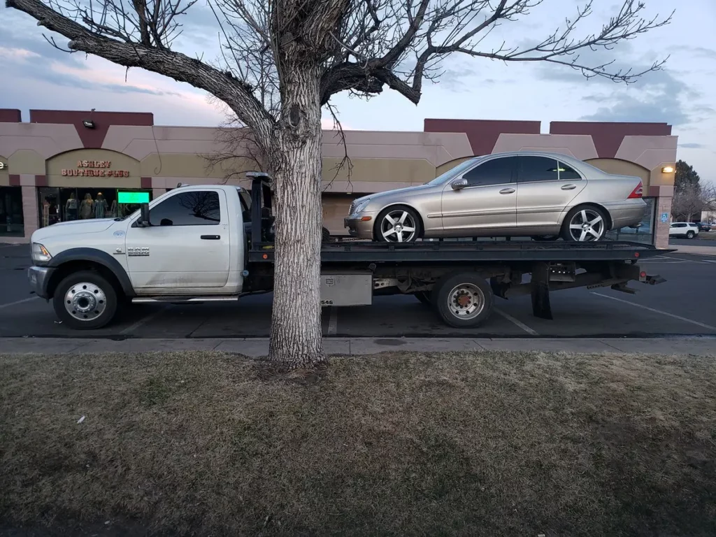 Ram flatbed hauling a silver sedan, junk car removal serving Fort Collins, CO