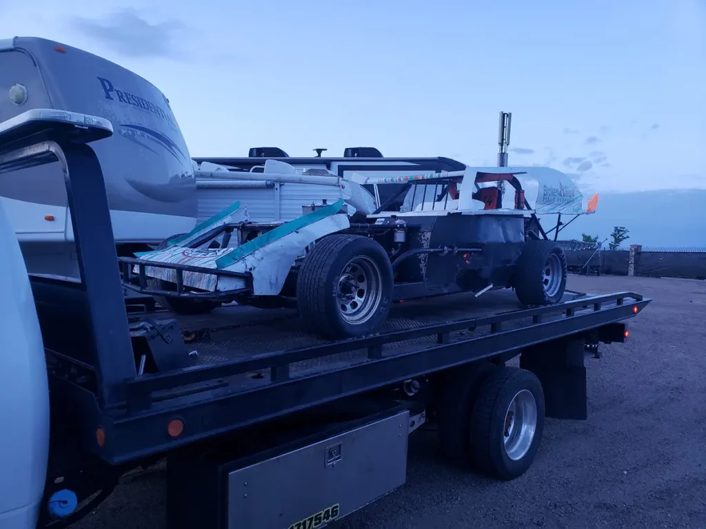 Open-wheel race car on the bed of a flatbed tow truck, junk vehicle pickup serving Highlands Ranch, CO