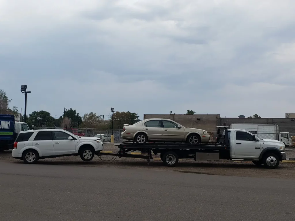Flatbed with a sedan on board and a white SUV in tow, cash for junk cars in the Estes Park, CO area