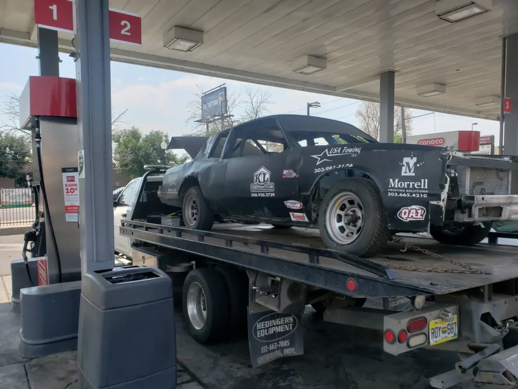 Old stock car race car loaded on a flatbed at a gas station, we buy junk cars in the Fort Collins, CO area