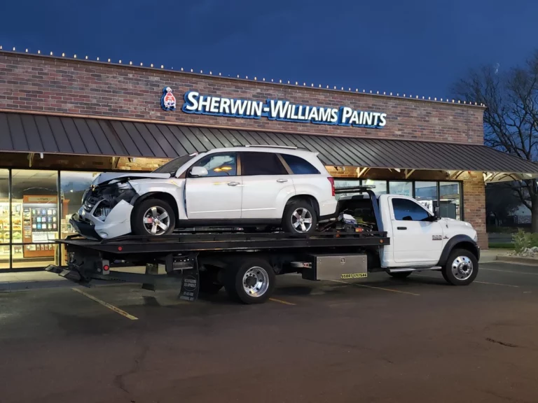 Totaled white SUV with front-end damage on Jorge's flatbed in Westminster, CO